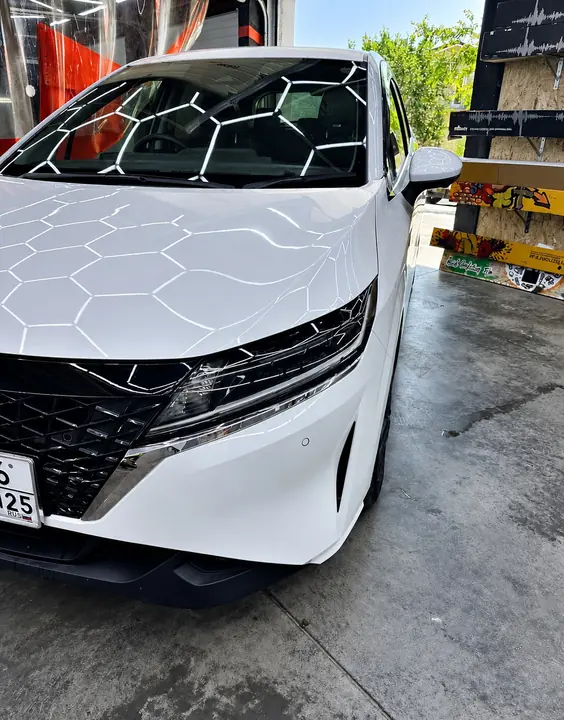 Белый Nissan Note: в лаке отражаются шестигранные лампы